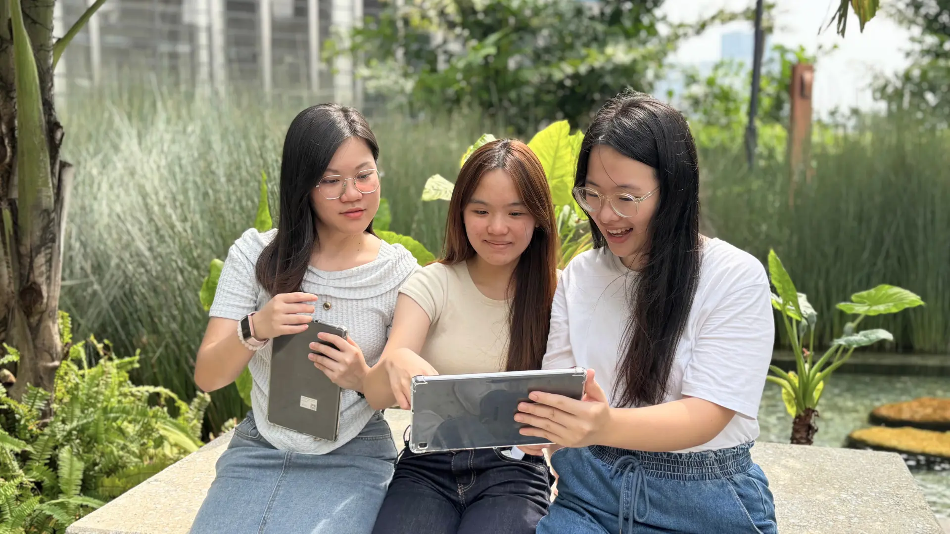 Three Plixitt team members sitting outdoors together, looking at a tablet